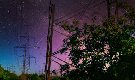 high voltage pole with Milky way on sky. industrial view of high voltage lines.