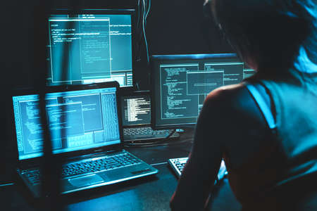 Software developer freelancer woman female work with program code on wide displays at night Develops...