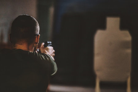 Man aiming a firearm toward a target at what appears to be an indoor shooting range. man is seen...