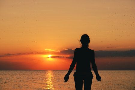 Silhouette of the woman standing lonely at the sea during beautiful sunset. Download imageの写真素材