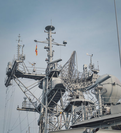 Close-up view of a naval ships mast with advanced radar and communication equipment, including antennas and sensors. A flag signals nationality or semaphoreの写真素材