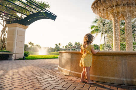 little girl looking into water fountain.の写真素材