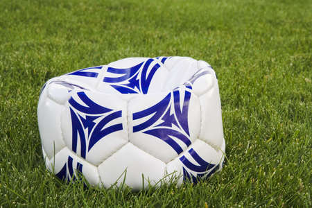 Flat white and blue soccer ball on lawnの写真素材