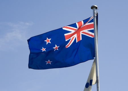 New Zealand flag blowing in the breeze against a blue sky.の写真素材