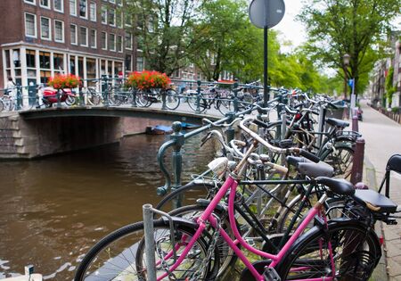 Large number of bike sparked along a canal and across a bridge in Amsterdam, The Netherlandsの写真素材