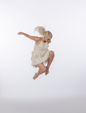 Girl contemporary dancer in studio against a white background in crème colored dressの写真素材