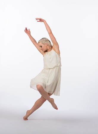 Girl contemporary dancer in studio against a white background in crème colored dressの写真素材