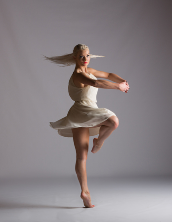 Girl contemporary dancer in studio against a white background in crème colored dressの写真素材