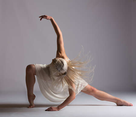 Girl contemporary dancer in studio against a white background in crème colored dressの写真素材