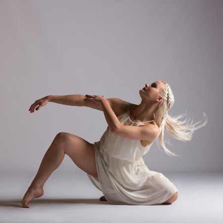 Girl contemporary dancer in studio against a white background in crème colored dressの写真素材