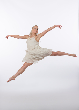 Girl contemporary dancer in studio against a white background in crème colored dressの写真素材