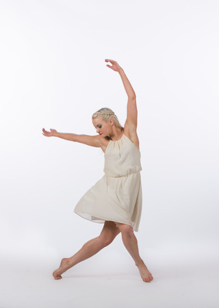 Girl contemporary dancer in studio against a white background in crème colored dressの写真素材