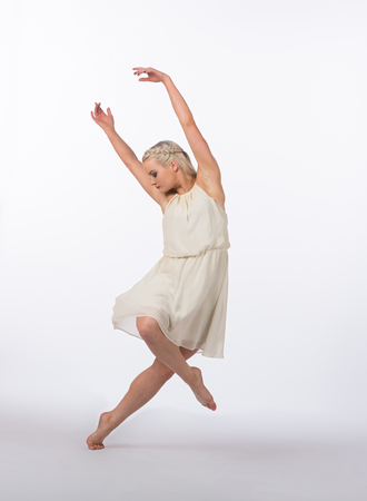 Girl contemporary dancer in studio against a white background in crème colored dressの写真素材