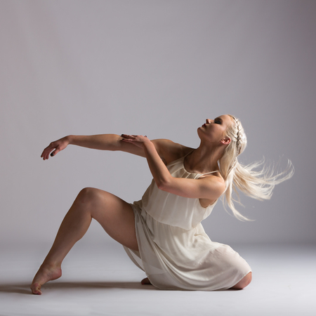 Girl contemporary dancer in studio against a white background in crème colored dressの写真素材