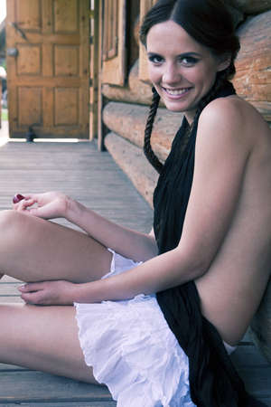 Eighteen girl sitting near a wooden house. Grape on the floorの写真素材