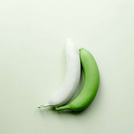Two creative bananas on green background, flat lay. Fruit minimalism poster. Exotic art fruits. Greenery top colorの写真素材