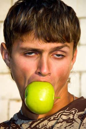 Portrait of a guy with the streaking hair, biting an appleの写真素材