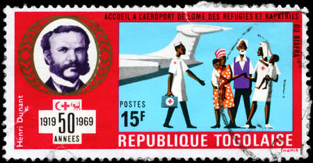 TOGO - CIRCA 1969: A Stamp printed in TOGO shows Henri Dunant and Red Cross workers meeting Biafra refugees at airport, series League of Red Cross Societies, 50th anniv., circa 1969のeditorial素材
