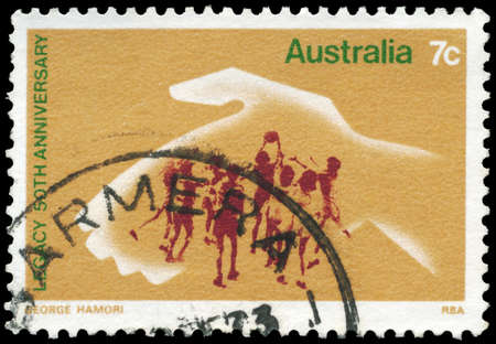 AUSTRALIA - CIRCA 1973: A Stamp printed in AUSTRALIA shows the Hand protecting playing Children, 50th anniversary of Legacy, an ex-servicemenâs organization, circa 1973の写真素材