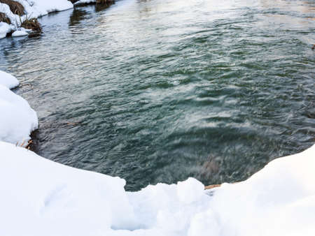 Winter landscape with seething water flowの写真素材