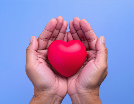 Hands holding red heart on blue background. Health care concept.の素材