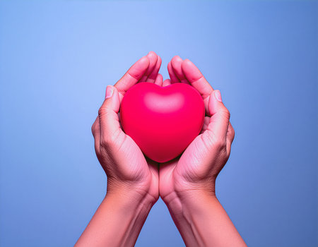 Red heart in female hands on blue background. Health care concept.の素材