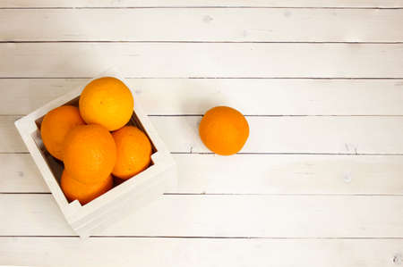 Oranges in a white box on a wooden backgroundの写真素材