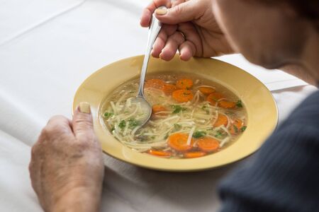 Eating home cooked soup wit carrots and noodelsの写真素材