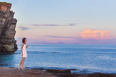 Young girl looks at sunset at the beachの写真素材