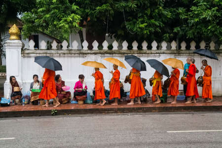 Luang Prabang, Laos - circa August 2015: Traditional Alms giving ceremony of distributing food to...