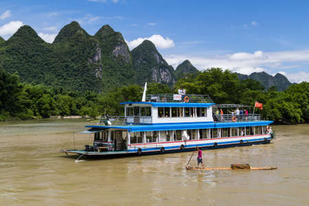 Guilin, China - circa July 2015: Cruise boat sails between karst mountains and limestone peaks of Li river in Chinaのeditorial素材