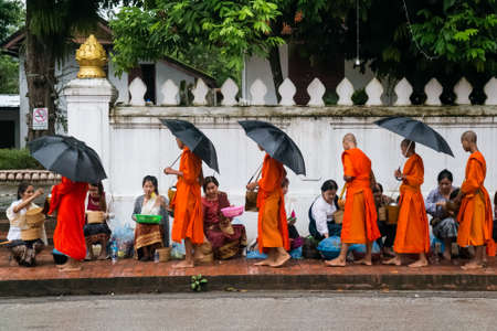 Luang Prabang, Laos - circa August 2015: Traditional Alms giving ceremony of distributing food to buddhist monks on the streets of Luang Prabang, Laosのeditorial素材