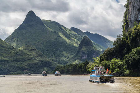 Guilin, China - circa July 2015: Cruise boat sails between karst mountains and limestone peaks of Li river in Chinaのeditorial素材