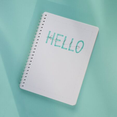Word "Hello" written in a notepad on mint backgroundの写真素材