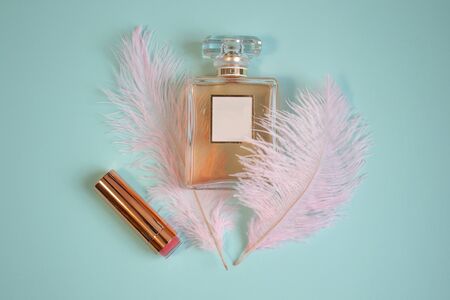 Perfume bottle and lipstick with feathers on turquoise backgroundの写真素材
