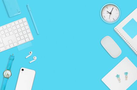 Flat layout of workplace. Keyboard, clock, notepad on a blue backgroundの写真素材