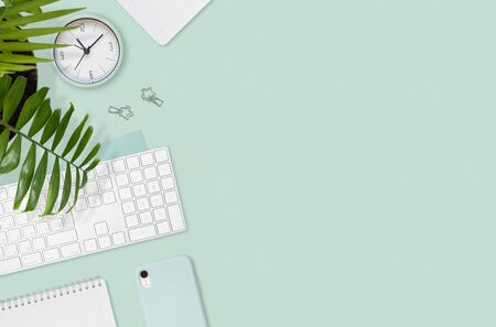 Flat layout of workplace. Palm, keyboard and empty notepad on mint green backgroundの写真素材
