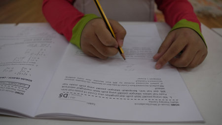 Student completes workbook exercises using pencil during study time.のeditorial素材