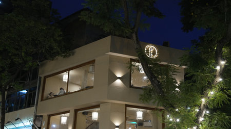 Contemporary cafÃ© building illuminated with warm lights during evening.のeditorial素材