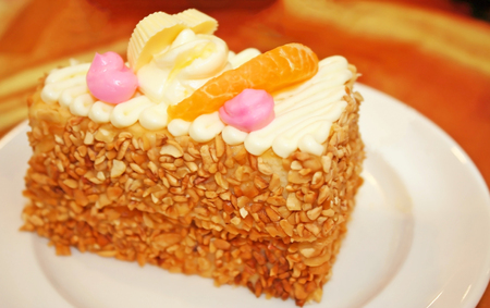 A piece of almonds cake with orange fruit on white plate