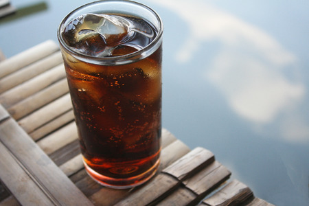 Glass of soft drink on bamboo raft in the lake