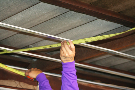 Workers measuring wood under roof, prepare for ceiling installation.の写真素材