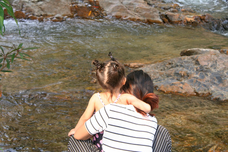 Asian child girl and her mom relaxing at riverの写真素材