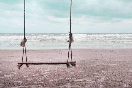 Single wooden swing with soft wind and landscape beach , natural sea background