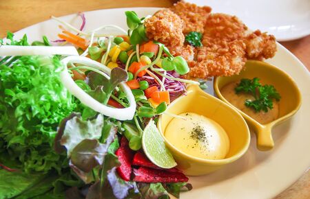 Muti fruit and vegetable salad , fried chicken with sweet sauce on white dish top view
