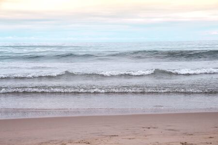 Waves breaking on sandy shore in the evening , natural  seascape background