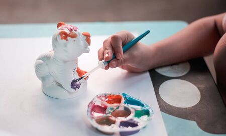 Little child asian girl  right hands painting color on the plaster tiger statue with bright blue...