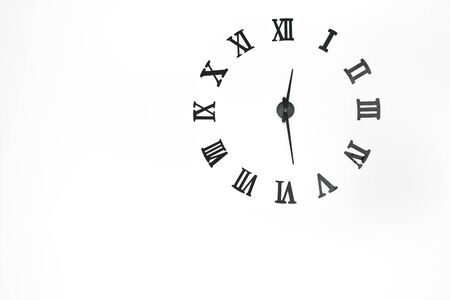 Clock patterns  with roman arabic numerals and clock hands on white concrete wall background and copy spaceの写真素材