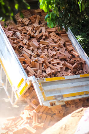 Many bricks unloading from tipper truck to the ground at construction site