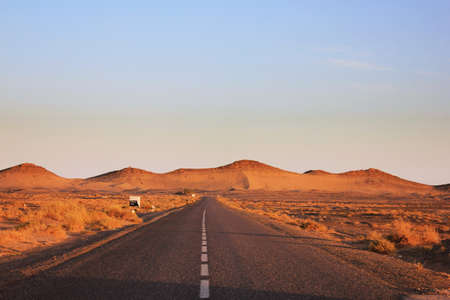 road running through the desert at sunsetの写真素材